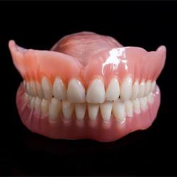 Full upper and lower dentures against dark background
