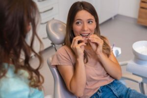 Dental patient holding Invisalign tray close to her mouth